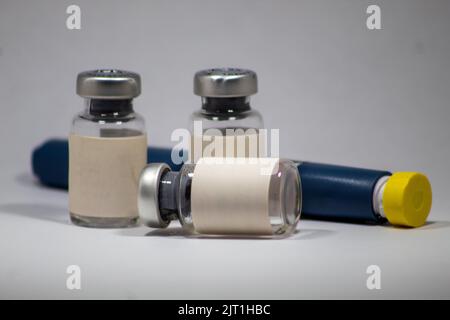 Fiale, fiale e aghi vuoti utilizzati per il trattamento medico, sfondo bianco isolato, focalizzazione selettiva, effetto rumore Foto Stock