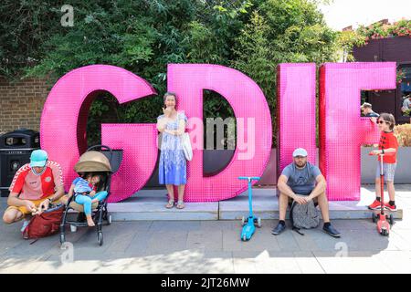 Londra, Regno Unito. 27th ago, 2022. La gente si siede e riposa sul logo del GDIF Greenwich and Docklands International Festival al Cutty Sark Gardens di Greenwich, dove questo fine settimana si svolgono alcune delle esibizioni del grande festival interattivo e gratuito di quest'anno. Credit: Imageplotter/Alamy Live News Foto Stock