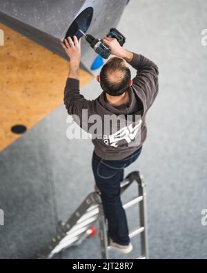 Un apparecchio di arrampicata che cerca di impostare un percorso nella palestra bouldering Foto Stock