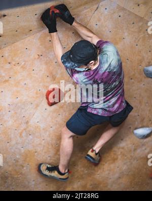 Un apparecchio di arrampicata che cerca di impostare un percorso nella palestra bouldering Foto Stock