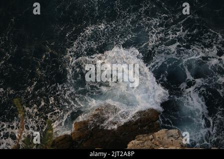 Un bel colpo di onde che si schiantano in una roccia e creano un grande tuffo Foto Stock