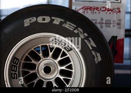 Un primo piano di una ruota di Formula 1 con un cerchione BBS e uno pneumatico Bridgestone potenza con un fondo di poster di gara Foto Stock