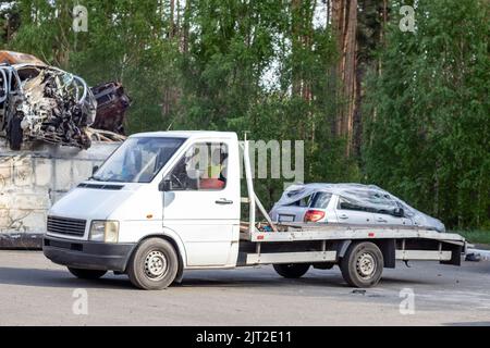 Un sacco di vecchie auto pronte per il riciclaggio. Rimozione della vettura tramite il carrello di traino. La vettura si sta preparando per essere caricata su un rimorchio. Vecchie auto distrutte in un recinto Foto Stock