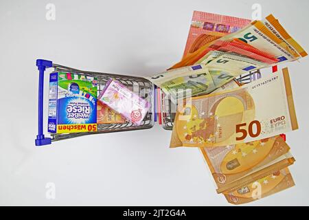 Viersen, Germania - Luglio 9. 2022: Primo piano di due modelli di carrelli con prodotti di marca e un sacco di banconote in euro in contanti Foto Stock