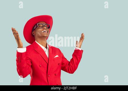 Allegro elegante e ispirato felice uomo dalla pelle scura che ringrazia con sollievo alzando le mani. Foto Stock