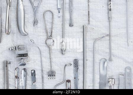 set di vecchi strumenti medici morsetti, bisturi e forbici su sfondo bianco, pratica medica Foto Stock