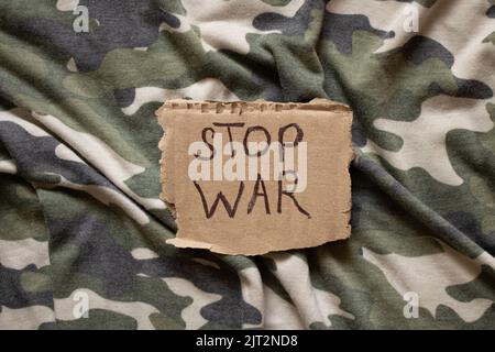 Stop war è scritto su carta che si trova sulla mimetizzazione militare del soldato, azione di protesta, abbigliamento militare Foto Stock