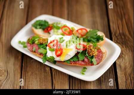 Sandwich all'uovo in camicia con peperoncino, scalogno e salame a fuoco selettivo orizzontale Foto Stock