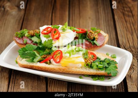 Sandwich all'uovo in camicia con peperoncino, scalogno e salame in primo piano orizzontale Foto Stock