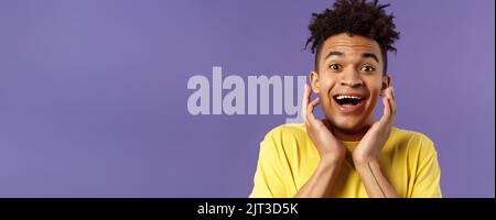 Primo piano ritratto di giovanotto estremamente felice e entusiasta sentire fantastiche notizie, guardando sorpreso ed eccitato, toccante volto nella gioia, sorridente ottimista Foto Stock