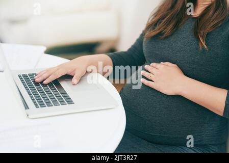 Lavorare da casa ha i suoi benefici: Una giovane donna incinta irriconoscibile che lavora da casa. Foto Stock