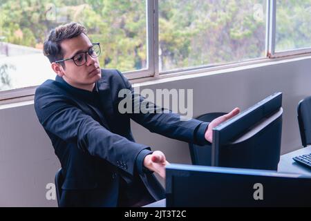 Sorpreso uomo in procinto di finire il suo lavoro sul computer. Sorpreso uomo d'affari con ciò che ha visto sul monitor. Ufficio con i computer da una finestra. Foto di alta qualità Foto Stock