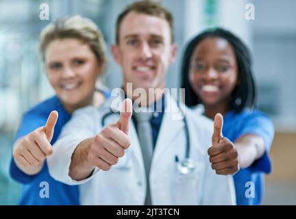 Tutto il meglio per la vostra procedura. Ritratto di un team di giovani medici fiduciosi che danno pollici in su. Foto Stock