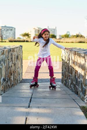 Questo è un modo più divertente di quanto pensassi. Una giovane ragazza pattinare a rotelle al parco. Foto Stock