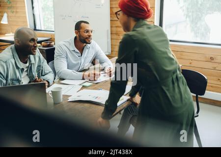 Gruppo di uomini d'affari multiculturali che hanno discussioni durante una riunione del consiglio di amministrazione. Diversi professionisti aziendali che condividono idee creative in un'area di lavoro Foto Stock