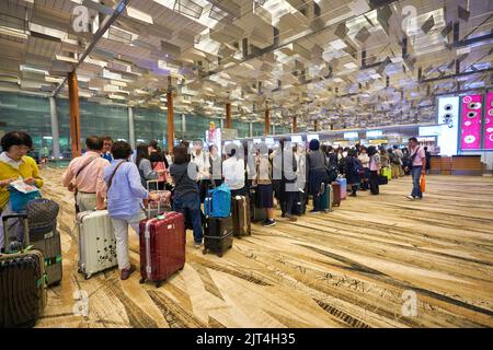 SINGAPORE - CIRCA GENNAIO 2020: Le persone sono in fila in attesa del check-in all'aeroporto Changi di Singapore. Foto Stock