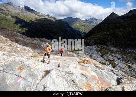 Madre e figlio camminano su rocce colorate su una morena del ghiacciaio su un bellissimo sentiero del ghiacciaio Innergschlöss fino al ghiacciaio di Schlatenkees, Tirolo orientale, Austria Foto Stock