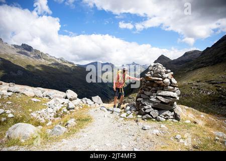 Ragazzo vicino a piramide di pietra escursioni su un bellissimo sentiero del ghiacciaio Innergschlöss fino al ghiacciaio Schlatenkees, parco nazionale Hohe tauern, Tirolo orientale, Austria Foto Stock