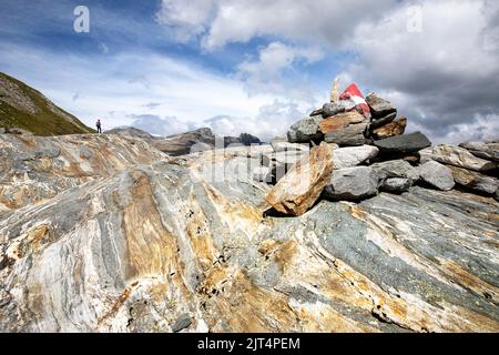 Donna che si arrampica su rocce colorate su una morena del ghiacciaio su un bellissimo sentiero del ghiacciaio Innergschlöss fino al ghiacciaio di Schlatenkees, Tirolo orientale, Austria Foto Stock