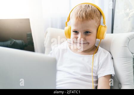 Un ragazzo in cuffia guarda lo schermo di un notebook. Foto Stock