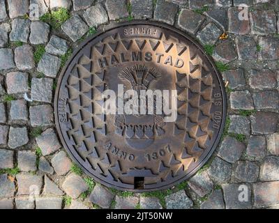 Halmstad, Svezia - 21 agosto 2022: Copertura del tombino della città di Halmstad sulla strada con pavimento in ciottoli, vista dall'alto Foto Stock