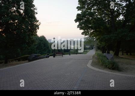 Sentieri pedonali nel parco cittadino. Panchine e lanterne d'epoca. Parco cittadino all'alba. Foto Stock