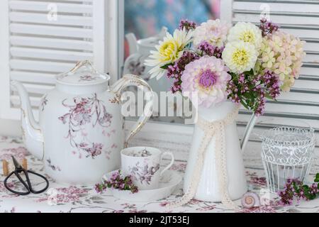 romantico arranemenrt con bouquet di dahlias bianco e viola e porcellana d'annata Foto Stock