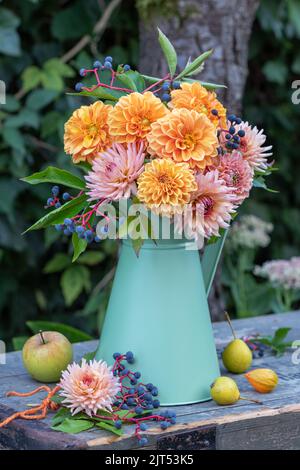 bouquet di fiori d'arancio e bacche di vino selvatico in brocca d'annata in giardino Foto Stock