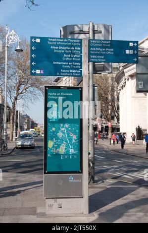 Vista sulla strada con insegna turistica, Dublino, Eire. Cartello bilingue che fornisce indicazioni per alcune delle principali attrazioni turistiche di Dublino. Banca d'Irlanda. Foto Stock