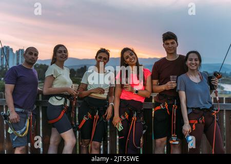 Gruppo di scalatori di roccia che scattano una foto e ridono con il tramonto sullo sfondo Foto Stock