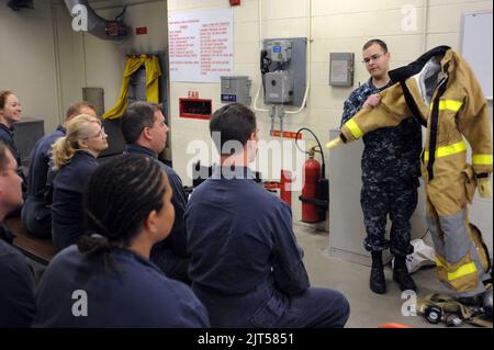 Mate 2nd Class di U.S. Navy Machinist, mostra un ensemble antincendio ai marinai con l'Executive Leadership Development Program durante un tour del Submarine Learning Center Detachment San 140113 Foto Stock