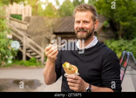 Giovane turista caucasico che mangia gelato al parco Foto Stock