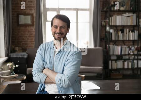 Felice uomo d'affari millenario fiducioso in piedi casual con le braccia incrociate Foto Stock