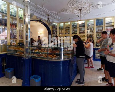 La gente fa una coda all'interno del famoso negozio Pasteis de Belem nel quartiere Belem di Lisbona, Portogallo. Foto Stock