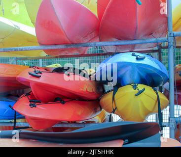 Canoe di diversi colori impilati nel porto di o Barqueiro in Spagna Foto Stock