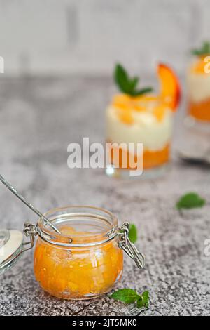 Vasetto di marmellata di pesche su sfondo bianco muro di mattoni Foto Stock
