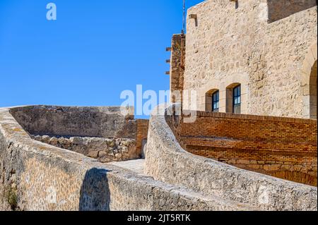 Architettura in pietra di mura fortificate all'interno del forte militare medievale. Vista dall'angolo basso con cielo blu Foto Stock