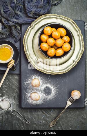 Cucina araba; dessert mediorientale/Ramadan Zalabya, o luqmat al- Kadi servito con miele e zucchero su sfondo scuro. Foto Stock