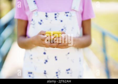 Donna senza volto che naviga sullo smartphone per strada Foto Stock