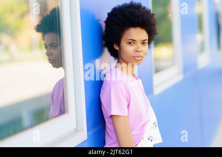 Donna nera in piedi vicino a casa blu Foto Stock
