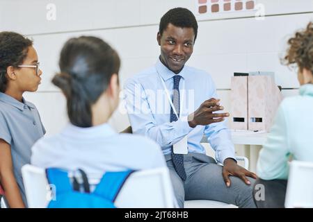 Ritratto di sorridente terapeuta maschile leader sessione di sostegno per i bambini Foto Stock