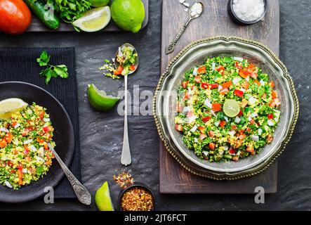Cucina araba; insalata tradizionale mediorientale. Insalata di Tabbouleh con pomodoro fresco, cetriolo, prezzemolo, menta, cipolla e bulgur. Vista dall'alto con primo piano. Foto Stock