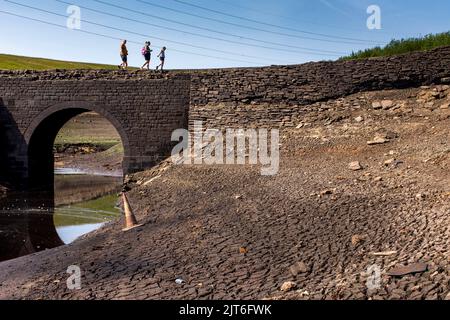 Ripponden, West Yorkshire, UK, 28th agosto 2022 UK Weather Baitings Dam è al suo livello più basso nella memoria recente. Il bacino idrico dello Yorkshire vicino a Ripponden è così asciutto che l'antico ponte a cavallo è stato esposto - sommerso da quando il bacino fu inondato negli anni '1950s - e il letto di quello che un tempo era un lago ora assomiglia ad un paesaggio desertico. Baitings è diventato un'attrazione turistica nelle ultime settimane, poiché i livelli nazionali delle acque nei serbatoi sono scesi al loro livello più basso dal 1995. Credit: Windmill Images/Alamy Live News Foto Stock