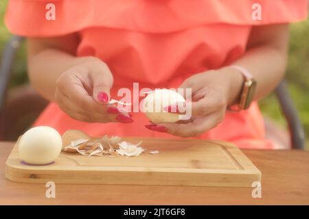 Donna irriconoscibile che taglia uovo sodo su tavola di legno all