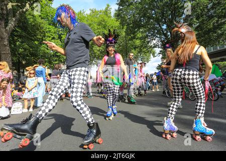 Londra, Regno Unito. 28th ago, 2022. Un gruppo incluso sui pattini a rotelle e in carrozzina davanti alla parata esegue acrobazie e intrattiene la folla. I partecipanti posano e Buon divertimento. La giornata della famiglia si svolge al Carnevale di Notting Hill con carri, bande d'acciaio e gruppi di danza che celebrano il ritorno del carnevale. Ci si aspetta che oltre un milione di persone partecipino a quello che quest'anno è considerato il più grande evento di strada in Europa. Credit: Imageplotter/Alamy Live News Foto Stock