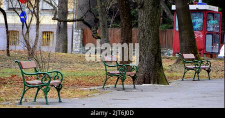 Una fila di panchine vuote sul lato di una passerella in un parco Foto Stock