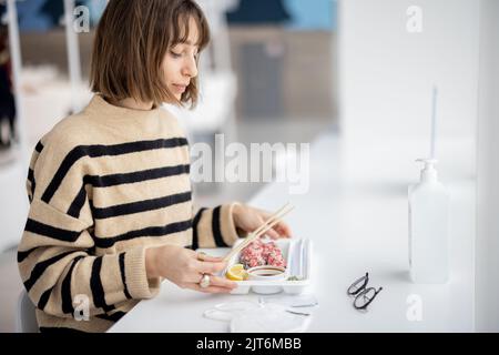 Donna che mangia sushi roll al ristorante Foto Stock