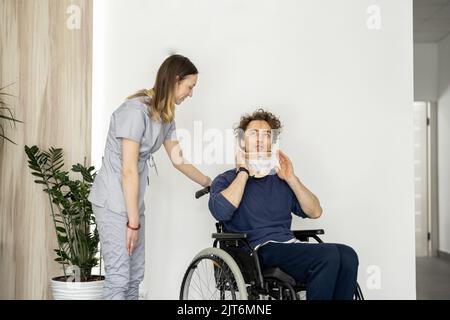 Il medico comunica con un uomo su una sedia a rotelle con lesioni al collo Foto Stock