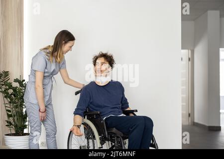 Il medico comunica con un uomo su una sedia a rotelle con lesioni al collo Foto Stock