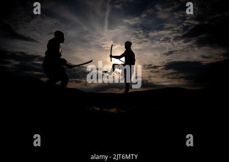 Silhouette di combattimento con la spada delle arti marziali al tramonto Foto Stock